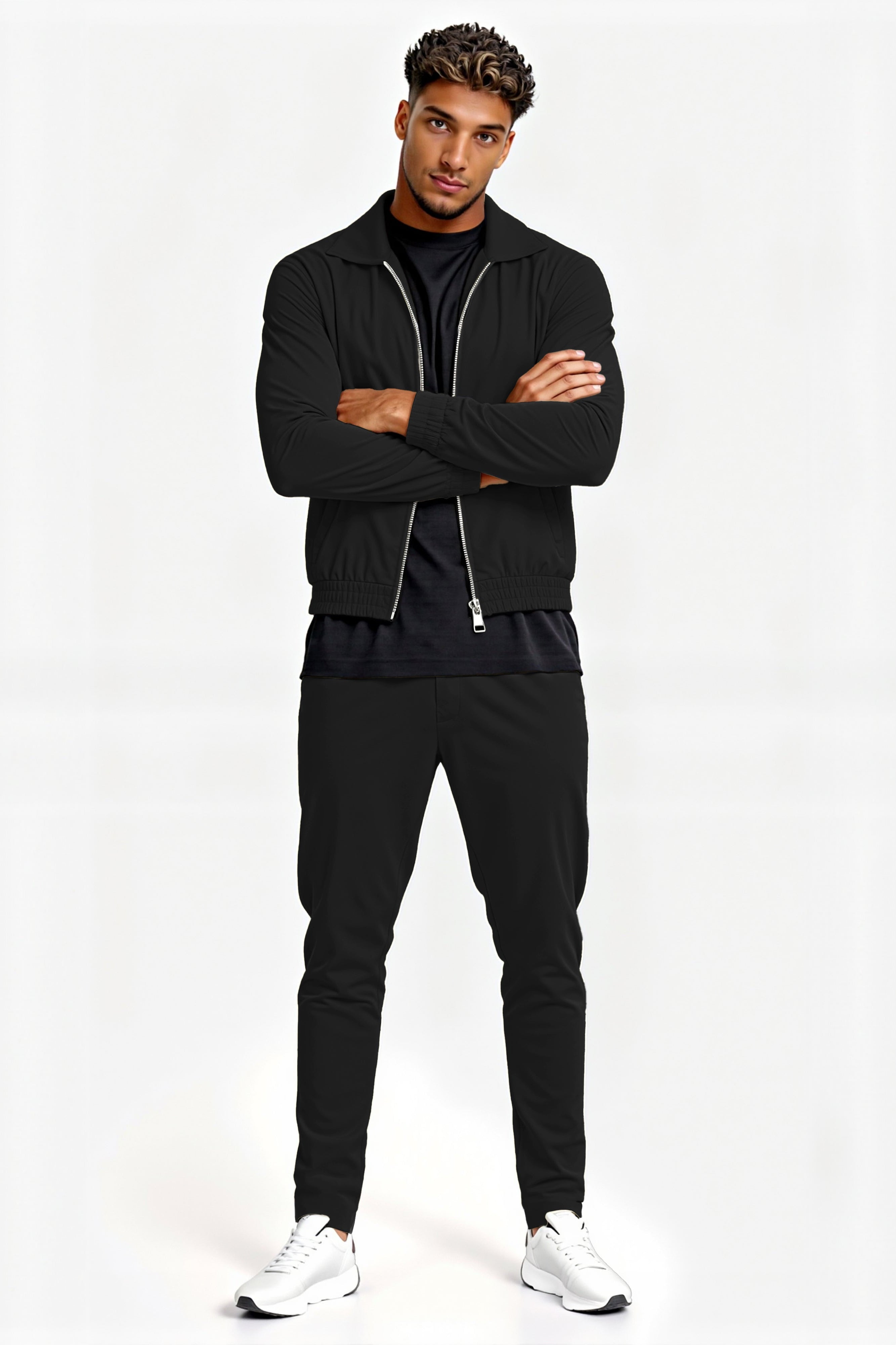 Man wearing a black tracksuit with white sneakers on a white background